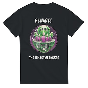 May include: Black t-shirt with a green and purple graphic of ghosts and candles in a circle. The text "BEWARE! THE IN-BETWEENERS!" is printed on the shirt.