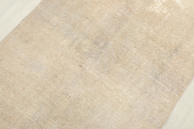 K&ouml;nnte beinhalten: Ein beigefarbener Teppich mit einem Used-Look. Der Teppich hat eine gewebte Textur und einen verblichenen, Vintage-Look. Die Farbe ist ein heller, neutraler Ton mit subtilen Farbvariationen. Der Teppich ist wahrscheinlich aus Naturfasern gefertigt.