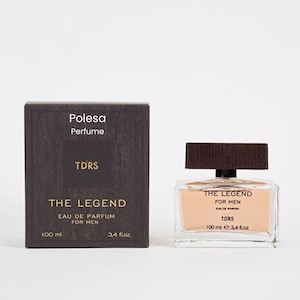 Puede incluir: Un juego de botella y caja de perfume rectangulares. La botella es transparente con un líquido de color melocotón claro. La caja es de color marrón oscuro con el texto "Polesa Perfume" y "The Legend". La botella contiene 100 ml o 3,4 fl oz.