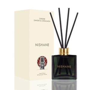 Peut inclure: Un diffuseur d'intérieur en verre vert foncé avec des bâtonnets noirs et un col doré, à côté d'une boîte crème. La boîte indique "Chinese Ginger & Cinnamon" et "NISHANE". Le diffuseur est pour la maison.