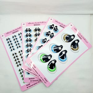 May include: Three sheets of adhesive resin doll eyes in various sizes. The sheets are pink with white borders and feature different colored eyes. The sizes are labeled as Ex Large, Large, Medium, and Small. The measurements are listed in inches and millimeters.