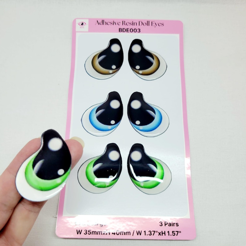 May include: Three pairs of adhesive resin doll eyes. The eyes are brown, blue, and green with black pupils. The eyes are 1.37 inches wide and 1.57 inches tall.