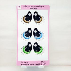 May include: Three pairs of extra-large adhesive resin doll eyes. The eyes are brown, blue, and green. Each pair is 1.37 inches wide and 1.57 inches tall.