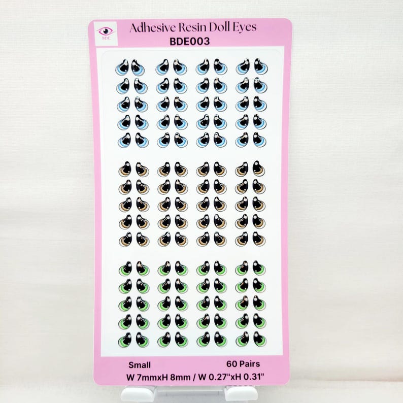 May include: A sheet of 60 pairs of small adhesive resin doll eyes. The eyes are in three colors: blue, brown, and green. Each eye is about 0.27 inches wide and 0.31 inches tall.