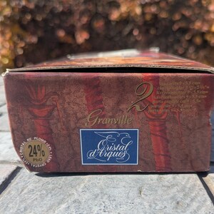 May include: A rectangular box with a burgundy and gold design. The box features the text "Granville" and the logo "Cristal d'Arques France". The box also has text indicating the contents are candle holders, with dimensions of 3.75 x 2.125 inches.