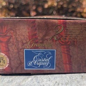 May include: A maroon box with gold lettering that reads "Granville" and the number "2". The box features the "Cristal d'Arques France" logo and a label indicating 24% PbO. The box also lists candle holder dimensions.