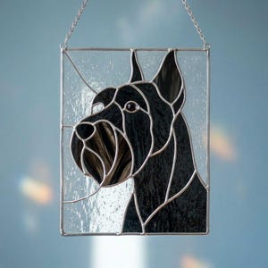 May include: A rectangular stained glass suncatcher featuring a profile of a black dog with a textured snout and ears. The dog is composed of dark, opaque glass pieces set within a silver metal frame, suspended by a thin silver chain for hanging.