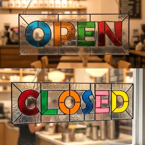 Peut inclure: Deux enseignes en vitrail, l'une indiquant "OPEN" en bleu, orange, vert et rouge, et l'autre indiquant "CLOSED" en rouge, vert, orange, bleu, rose et jaune. Les deux enseignes sont rectangulaires et suspendues par des chaînes.