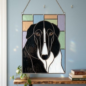 May include: A rectangular stained glass panel featuring a black and white dog portrait with a white blaze on its face. The dog is set against a background of pastel-colored glass rectangles in shades of light green, blue, peach, and lavender.