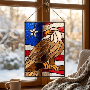 May include: Stained glass panel depicting an American flag and a bald eagle. The panel features a blue section with a white star, red and white stripes, and a detailed eagle in brown, white, and yellow. It is suspended by a chain.