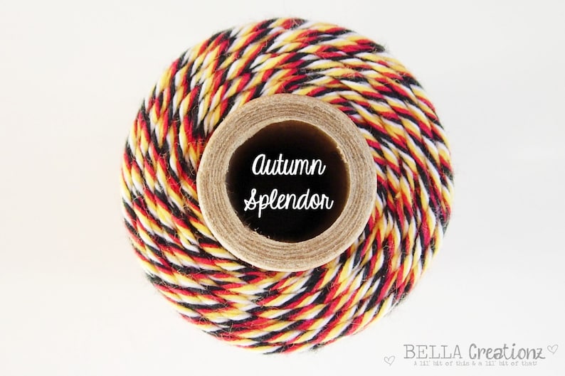 May include: A spool of twine with black, red, and yellow stripes. The spool is labeled "Autumn Splendor".