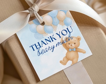 May include: A gift tag with a watercolor illustration of a teddy bear holding balloons. The tag reads "THANK YOU beary much" in navy blue script. The balloons are light blue and beige. The tag is tied to a gift with a beige ribbon.