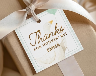 May include: A gift tag with a watercolor illustration of a goose holding a balloon. The tag reads "Thanks for Honkin' By!" with the name "Emma" below. The tag is tied to a wrapped gift with a cream-colored ribbon.