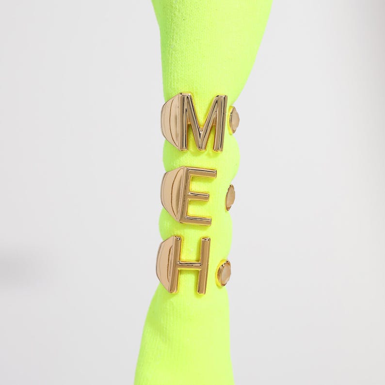 Neon green sock displaying gold monogram rings with the letters "M," "E," and "H" stacked on the ankle.
