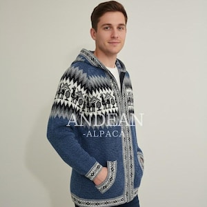 Peut inclure: Veste à capuche zippée bleue avec un motif en blanc, noir et gris. Le motif détaillé représente des lamas et des maisons. Le texte "ANDEAN - ALPACA" est imprimé sur le devant.