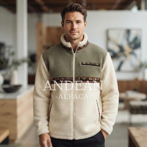 May include: A cream and olive green fleece jacket with a full-length front zip, a high collar, and a horizontal patterned band across the chest. The jacket features a small zipped chest pocket and the text ANDEAN-ALPACA printed on the front.