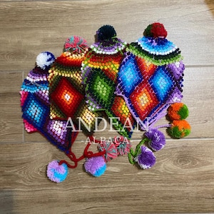 Può includere: Una collezione di cappelli in lana di alpaca colorati, lavorati a mano, con motivi a rombi e pompon. I cappelli presentano tonalità vivaci di rosso, blu, verde e viola. Il testo "ANDEAN ALPACA" è visibile.