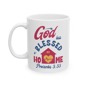 May include: White ceramic mug with the words "God has Blessed My Home" in red, blue, and gold. The design includes a house graphic with a heart and the Bible verse Proverbs 3:33.