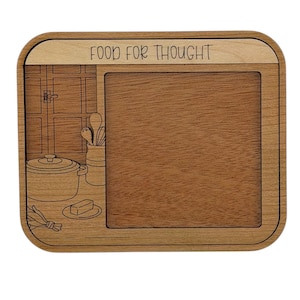 May include: Wooden cutting board with a rectangular design and rounded corners. The top section features the text "FOOD FOR THOUGHT". The left side has a kitchen scene with a pot, utensils, and a window. The center is a blank space for food preparation.