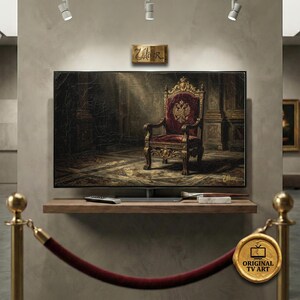 Puede incluir: Una pantalla de televisión muestra una pintura de una silla real con un asiento de terciopelo rojo y detalles dorados. La obra de arte está ambientada en una habitación oscura. La pantalla está sobre una estantería de madera con un mando a distancia y materiales de arte.