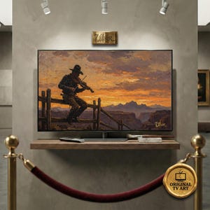 Könnte beinhalten: Ein großer Flachbildfernseher zeigt ein Gemälde mit Western-Motiv eines Cowboys, der bei Sonnenuntergang Geige spielt. Das Kunstwerk zeigt einen Cowboy mit Hut, der auf einem Holzzaun sitzt. Der Fernseher ist auf einem Holzregal montiert.