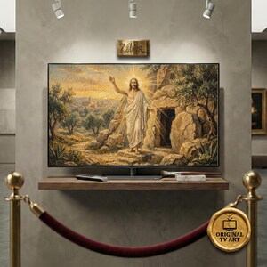 Può includere: Un grande televisore a schermo piatto mostra un dipinto religioso di una figura in abiti bianchi con un'aureola radiosa. Il televisore è montato su una mensola di legno con un telecomando e altri oggetti. L'immagine è etichettata "Original TV Art."
