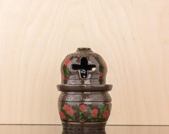 May include: A brown ceramic incense burner with a floral design. The burner has a cross-shaped opening on the top and a round base.