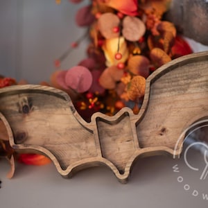 A wooden bat-shaped serving tray with three compartments. The tray is made of natural wood and has a rustic finish. The tray is perfect for serving snacks,  or other small items. The tray is also a great decorative piece for any home.