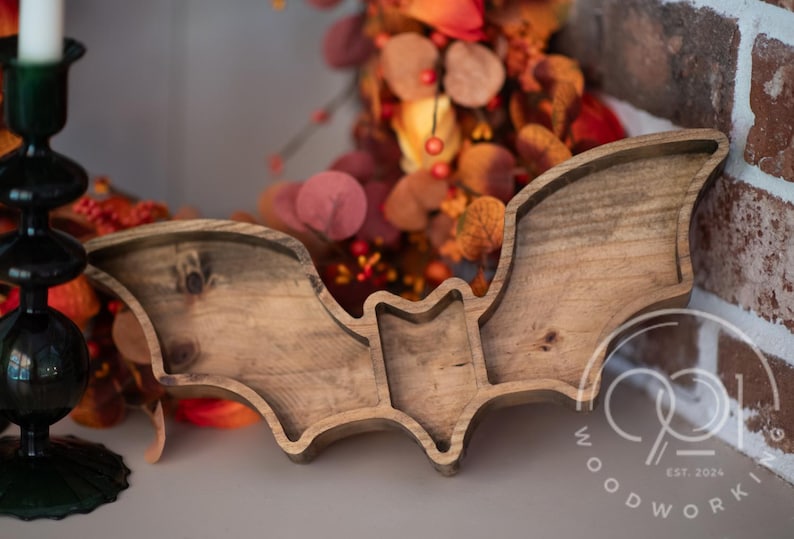 A wooden bat-shaped serving tray with three compartments. The tray is made of natural wood and has a rustic finish. The tray is perfect for serving snacks,  or other small items. The tray is also a great decorative piece for any home.