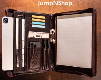 May include: Open brown leather portfolio with multiple compartments, including card slots, a phone pocket, and a notepad. The portfolio contains a tablet, cards, a phone, and a notepad. The JumpNShop logo is visible in the top center.