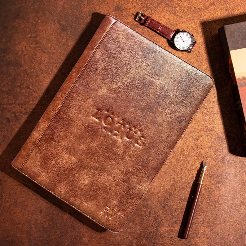 May include: A brown leather portfolio with the embossed text "LOTUS" and the initials "RV".