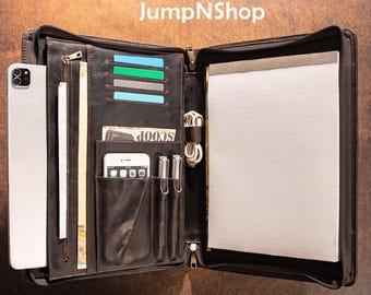 May include: A dark brown leather portfolio with multiple pockets, a notepad, and a zipper closure. The portfolio contains a smartphone, pens, credit cards, and a wad of cash. The text "JumpNShop" is visible at the top.