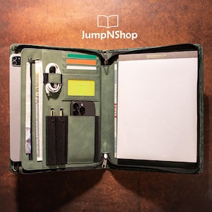 May include: Open green leather portfolio with multiple compartments for a tablet, phone, cards, pens, and a notepad. The portfolio is open, revealing the interior organization and JumpNShop logo.