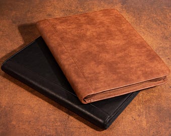 May include: Two leather document holders. One is black, and the other is brown. Both have a zipper closure and a textured surface. The brown document holder is on top of the black one.