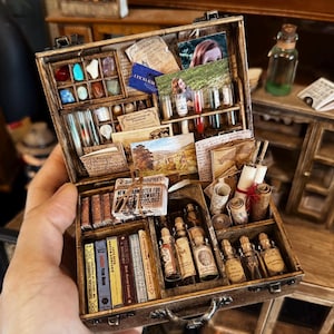 Puede incluir: Un maletín de madera en miniatura con varios compartimentos, lleno de libros diminutos, viales, pergaminos y gemas de colores. El maletín también contiene fotografías en miniatura y papeles impresos, creando una escena detallada y caprichosa. El maletín está abierto, mostrando los detalles.