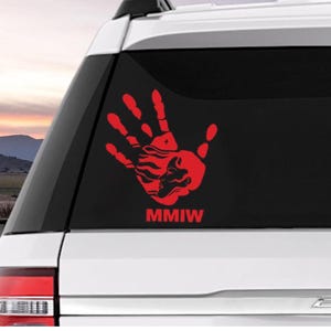 Peut inclure: Autocollant de main rouge avec un buffle stylis&eacute; &agrave; l'int&eacute;rieur et le texte "MMIW" sur une vitre de voiture blanche.