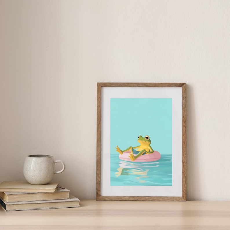 May include: A framed illustration of a green frog wearing blue shorts and relaxing on a pink inflatable ring in a blue pool with a reflection of the ring in the water.