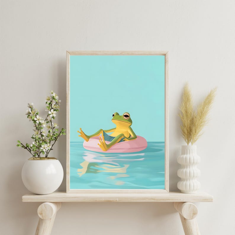 May include: A green frog wearing blue shorts floats on a pink inflatable ring in a turquoise blue pool. The frog is looking to the right and has its legs outstretched. The pool is calm and reflects the sky.