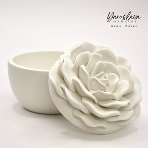 Könnte beinhalten: Weiße Keramik-Schmuckschatulle mit einem Deckel in Form einer großen, weißen Rose. Die Schachtel ist geöffnet und der Deckel liegt daneben. Die Schachtel ist von Yaroslav Mariani Home Décor.