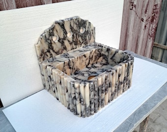 May include: A white and grey marble sink with a decorative backsplash. The sink is rectangular in shape and is surrounded by a series of vertical ridges.