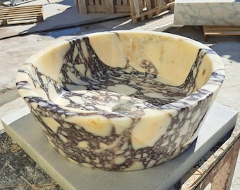 May include: A white and purple marble sink with a round shape and a smooth, polished finish. The sink has a unique, swirling pattern of white and purple marble.