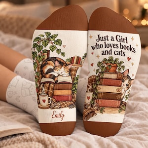 May include: A pair of white socks with brown toe and heel sections. The left sock features a calico cat sleeping on a stack of books, a potted plant, a coffee mug, and the name Emily. The right sock displays the text Just a Girl who loves books and cats, a stack of books, a potted plant, and a cat peeking out.