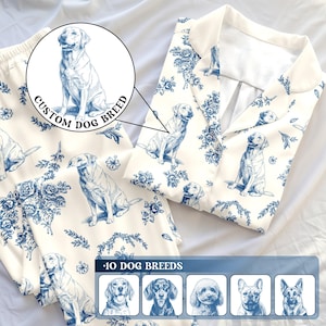 K&ouml;nnte beinhalten: Cremefarbenes Pyjama-Set mit einer blauen Hundeillustration und floralem Muster. Das Set besteht aus einem Hemd mit Kn&ouml;pfen und einer Hose. Der Text "CUSTOM DOG BREED" ist sichtbar. Das Bild zeigt auch eine Auswahl an Hunderassen.