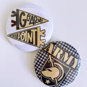 May include: Two round buttons with the text "GO ARMY WEST POINT" and a black and gold design. One button has a white background, and the other has a black and white checkered pattern with the word "ARMY" and a gold emblem.