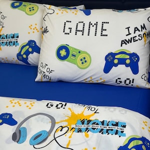 May include: White gaming-themed bedding set with blue and green controller graphics and the word "GAME". The set includes pillowcases and a fitted sheet with the phrases "I AM AWESOME" and "OUT OF CONTROL".