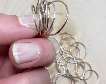 May include: A collection of hammered gold and silver stacking rings. The rings are all different sizes and are stacked on top of each other.