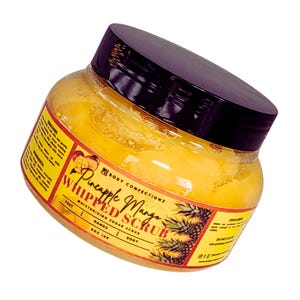 May include: A yellow jar of Pineapple Mango Whipped Scrub, a moisturising sugar scrub for feet, hands, and body. The jar has a black lid and a yellow label with the product name and ingredients.