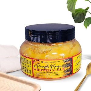 May include: A yellow jar of Pineapple Mango Whipped Scrub, a moisturising sugar scrub for feet, hands, and body. The jar has a black lid and a label with a pineapple and mango design.