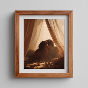May include: A framed print featuring a couple in an intimate embrace under draped fabric. The image has warm tones, with soft lighting and a focus on the couple. The frame is made of wood.
