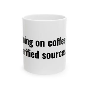 Könnte beinhalten: Ein weißer Keramikbecher mit schwarzem Text, der Running on coffee and verified sources lautet. Der Becher hat eine zylindrische Form mit einer glatten Oberfläche und einem Standardhenkel, wobei die Botschaft deutlich auf der Vorderseite steht.